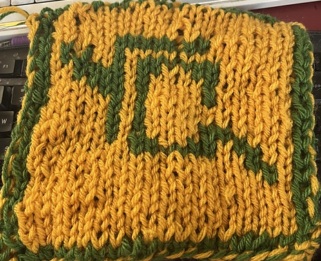 A knitted blanket square, featuring the the Astrologian job stone from Final Fantasy XIV. It looks like a stack of playing cards, outlined in green, on a gold background. This is the back view. FFXIV Astrologian Square, back