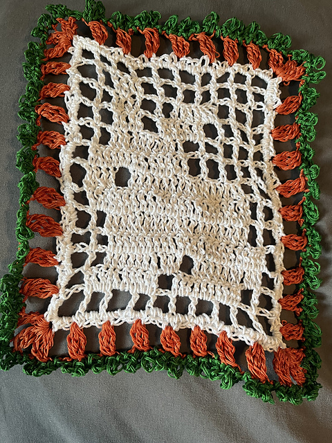 A rectangular filet crocheted doily of a bunny, edged in a border of carrots. Bunny Doily