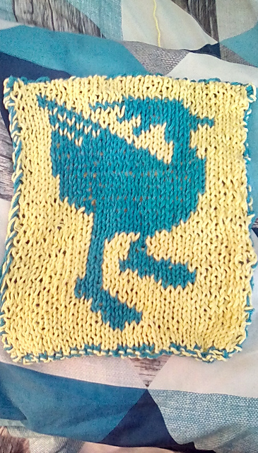 A double knit hotpad featuring a chocobo. This is the back view, which is a complete reverse of the front. It shows a teal chocobo on a yellow background, facing the opposite direction. Chocobo Hotpad, back