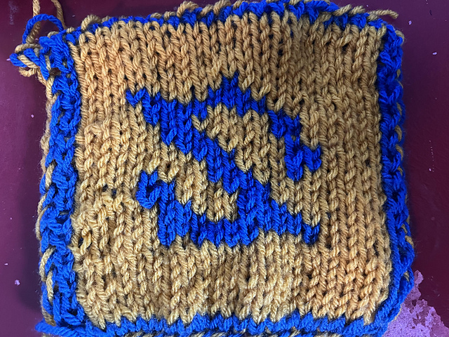 A knitted blanket square, featuring the the Astrologian job stone from Final Fantasy XIV. It looks like a reversed royal blue 'Z' on a gold background. This is the back view. FFXIV Gunbreaker Square, back