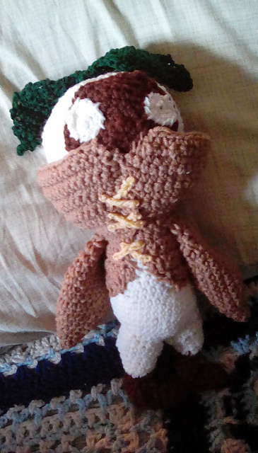 A crocheted mandragora from the Final Fantasy franchise. It has a white body with dark brown face. A green leaf is sprouting from its head. Mandragora