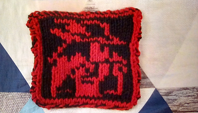 A knitted blanket square of the Red Mage sprite from the first Final Fantasy game. This is the back view, showing the character outlined in red on a black background. Red Mage Square, back