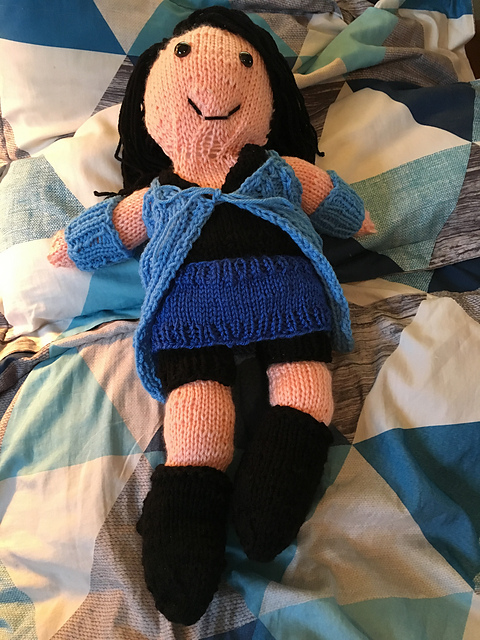 A knit doll of Rinoa from Final Fantasy VIII. She's got long black hair and brown eyes. She's wearing a black tank top, black shorts, and black boots. She's also got on a long blue duster and gauntlets, and a royal blue cumberband. Rinoa from Final Fantasy VIII