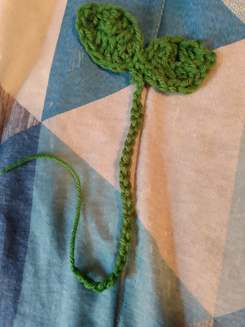A crocheted green bookmark. It's got a long crochete chain with two budding leaves at the top. Sprout Bookmark